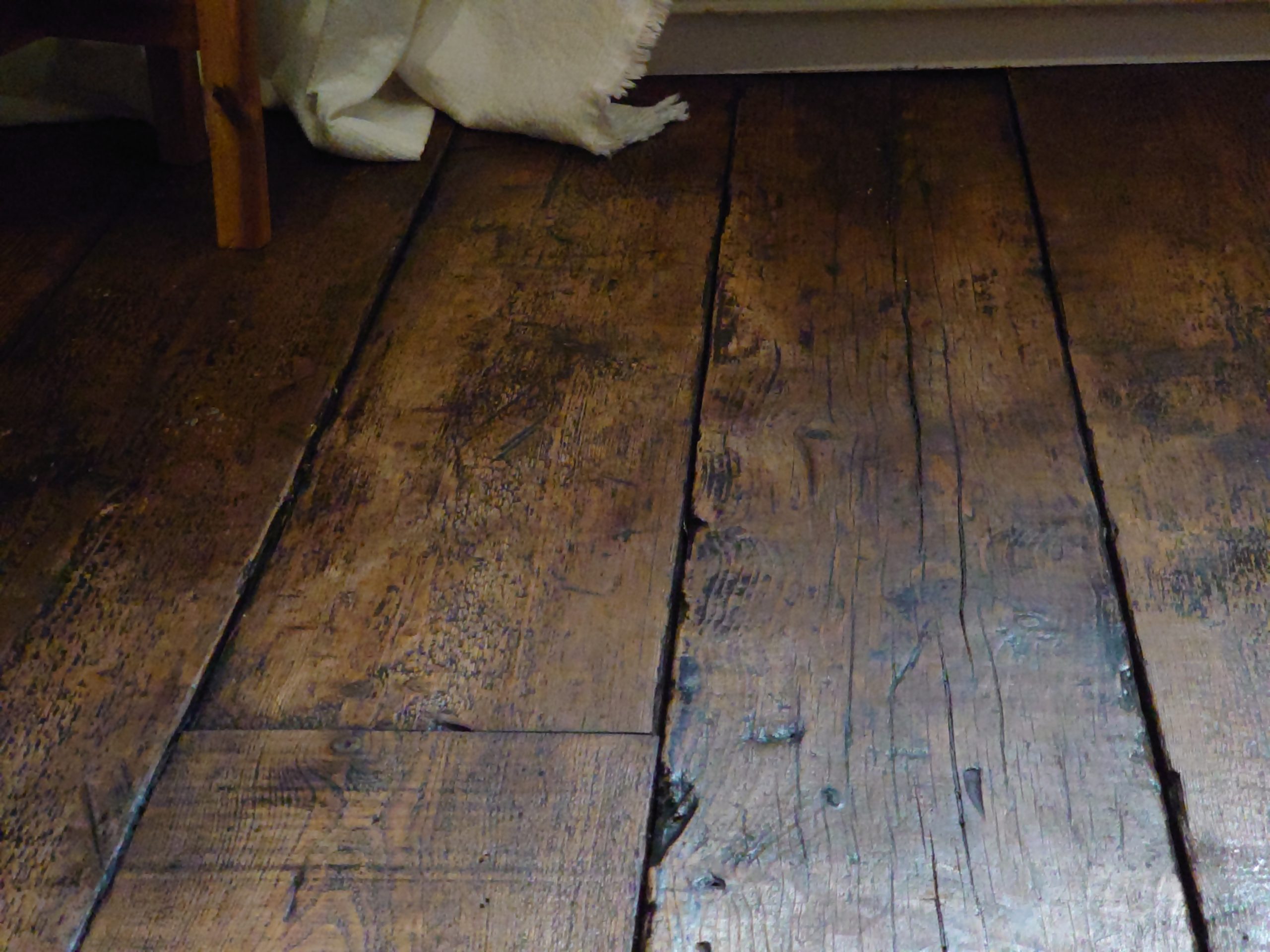 Close up detail of reclaimed pine scaffold board flooring stained and treated to look like antique oak