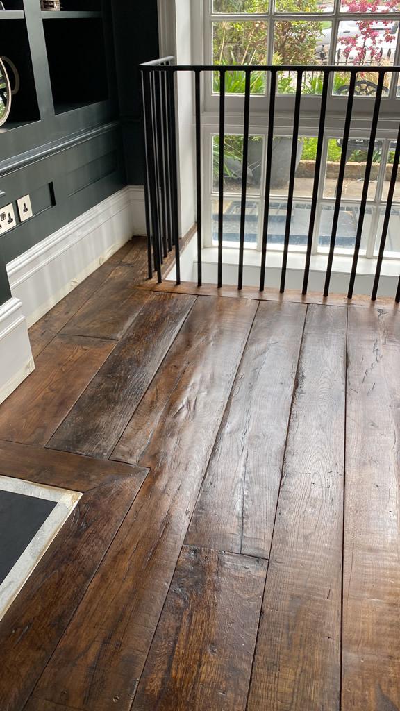 Antique reclaimed oak traditional wood flooring laid in a house in New York, showcasing dark stain finish and rustic edging