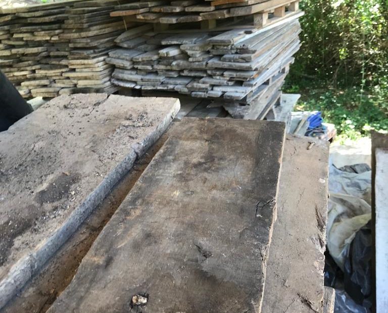 Stack of pitsawn floor boards with a stack of pallets in the background