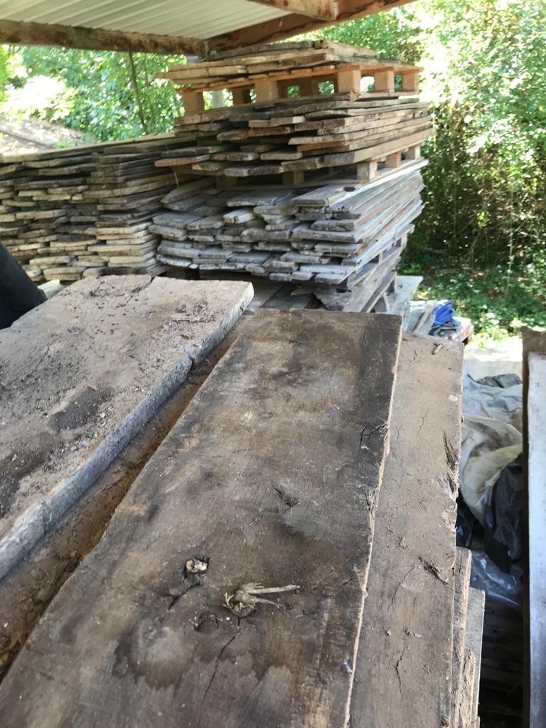 Stack of pitsawn floor boards with a stack of pallets in the background